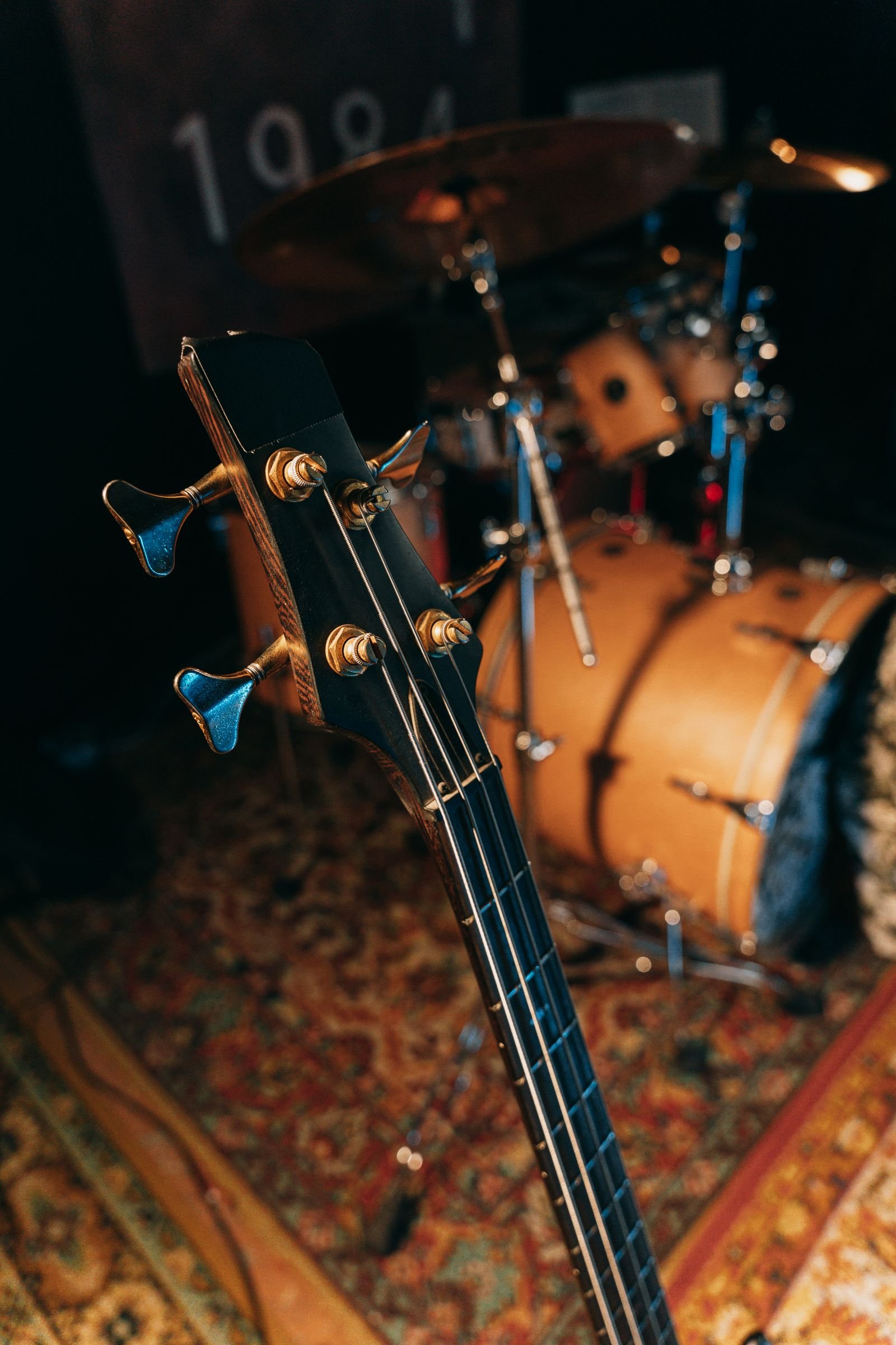 Bass headstock and drum kit with a banner reading 1994 in warm light