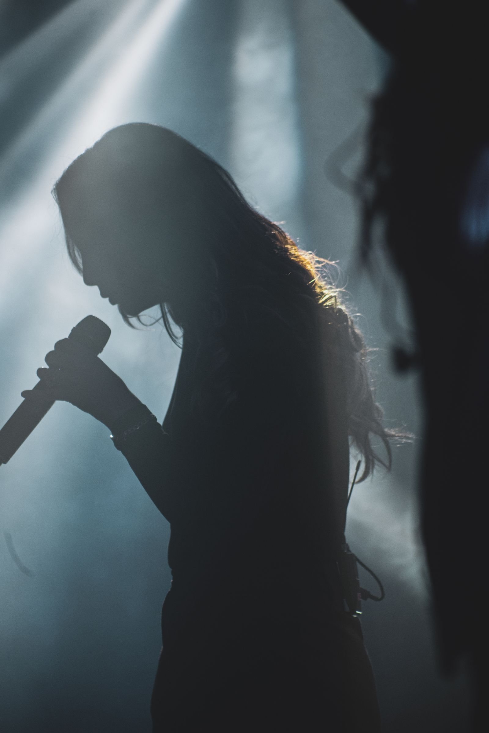 A dramatic singer silhouette under stage lights, moody and atmospheric