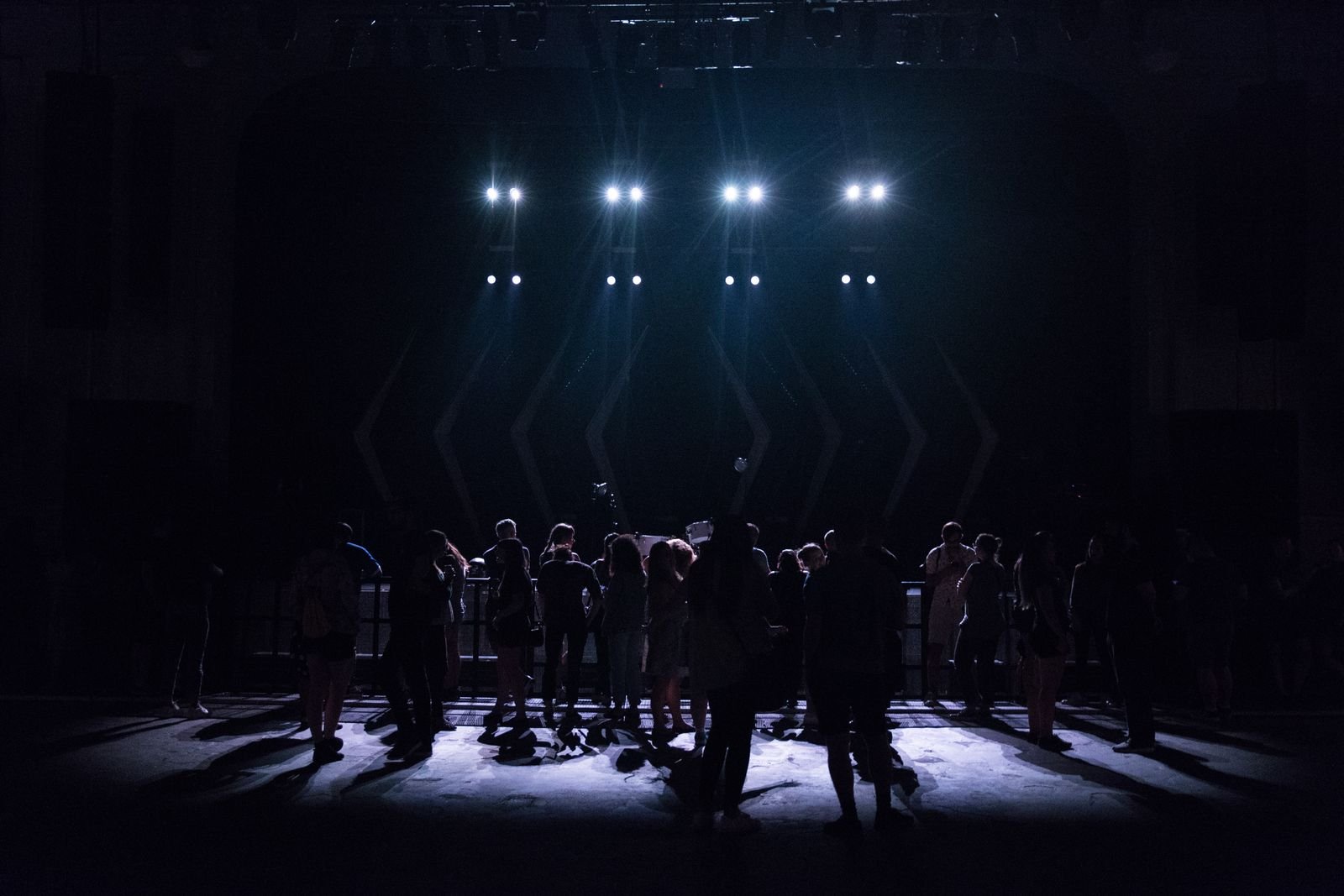 Dark venue with silhouetted figures under stark white lights